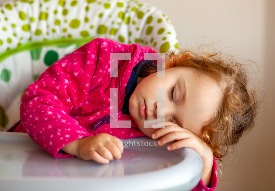 Exhausted little girl asleep in the high chair after school.