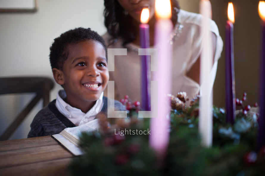 mother and son lighting an Advent wreath and reading a Bible 