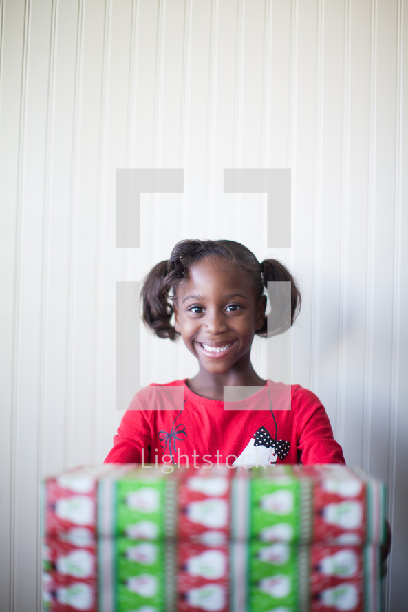 a girl child holding a wrapped Christmas gift 