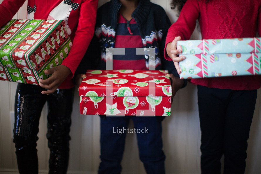 siblings holding wrapped Christmas gifts 