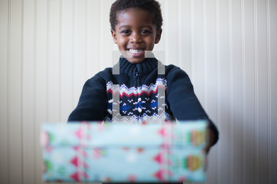 a boy child holding a wrapped Christmas girt 