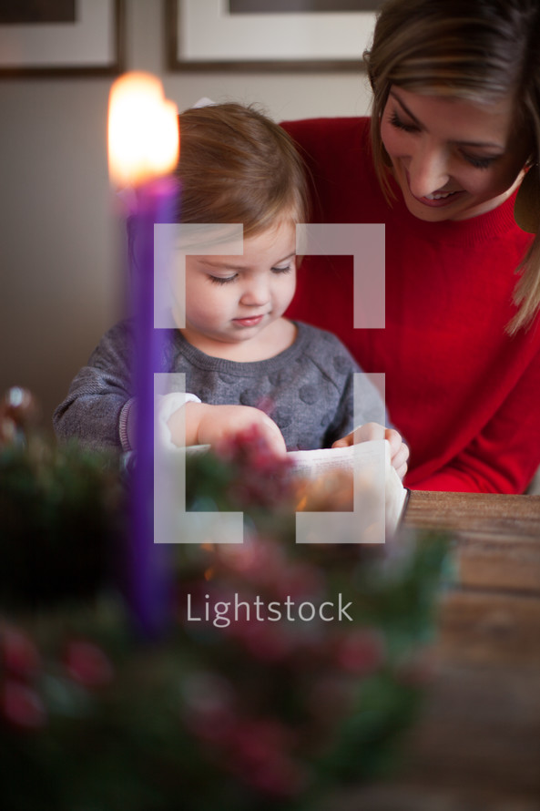 mother and daughter reading a Bible in front of an Advent wreath 