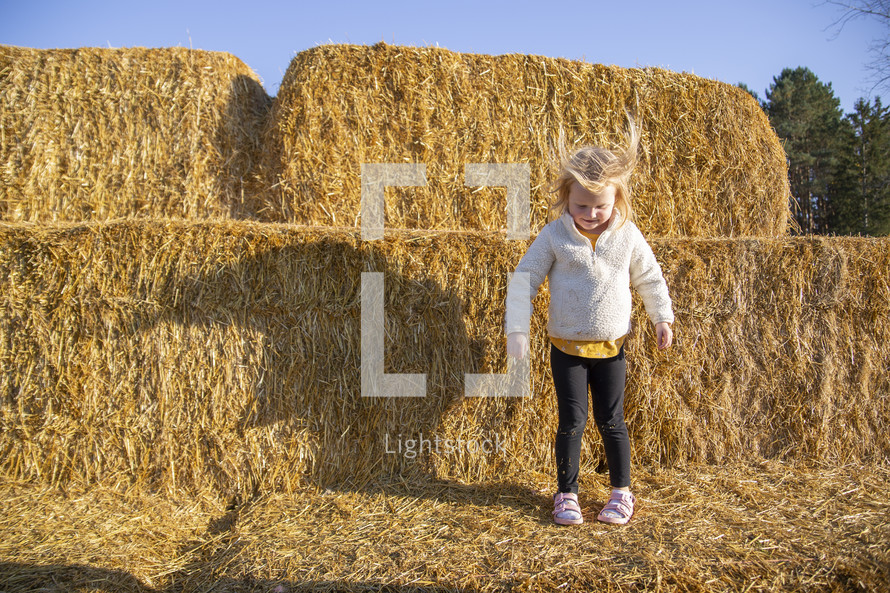 Little girl jumping in the hay