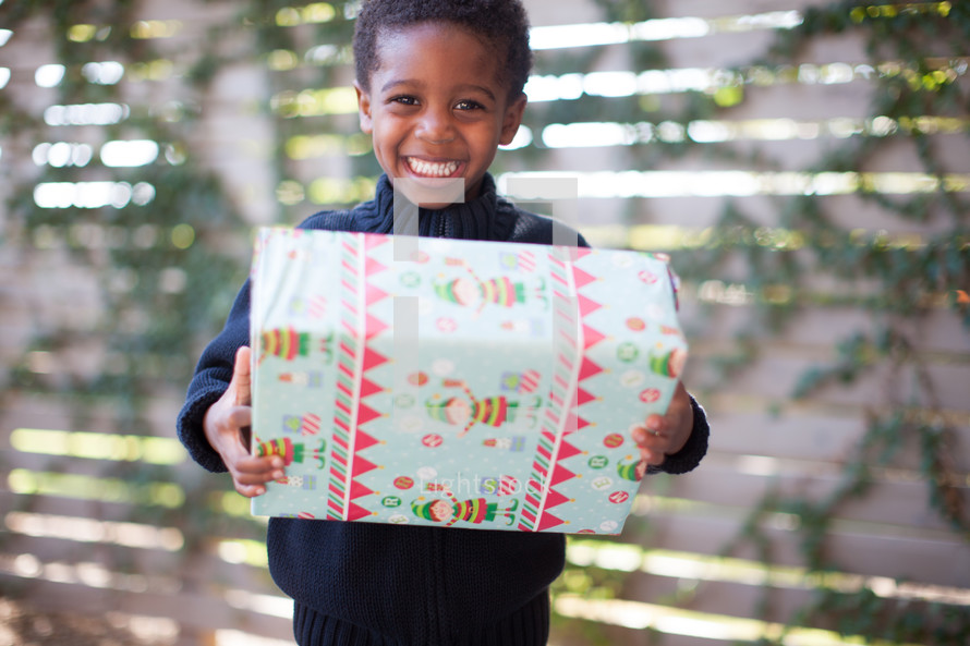 a boy child holding a wrapped Christmas gift 