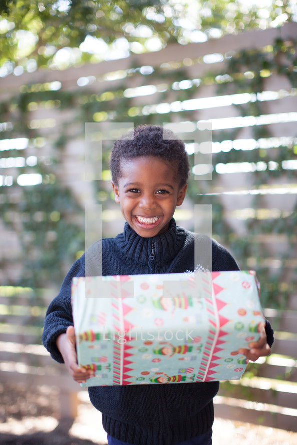 a boy child holding a wrapped Christmas gift 