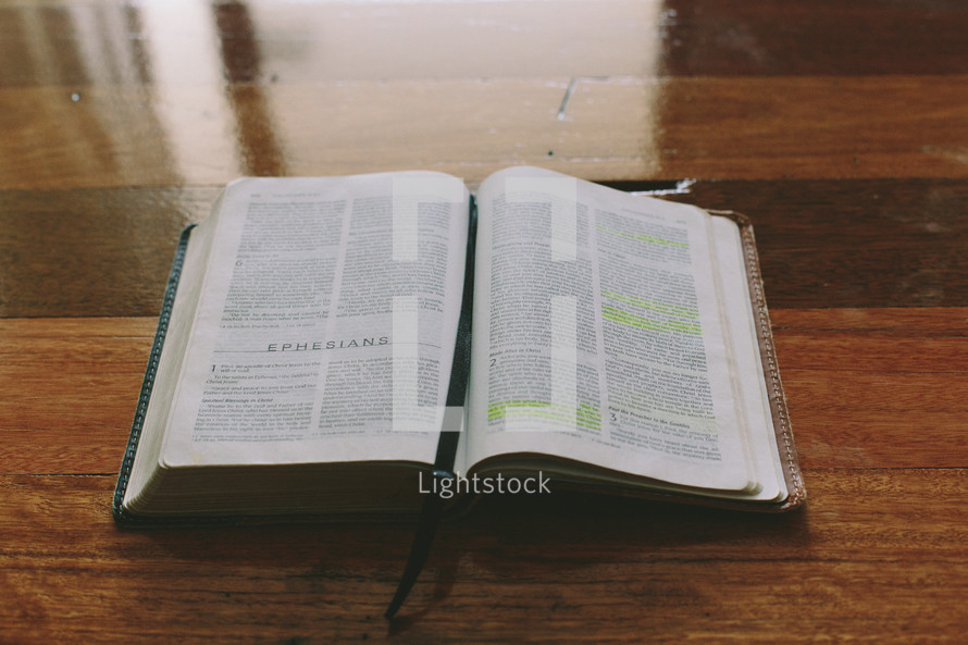 Bible open to Ephesians on a wooden table.