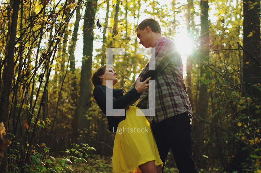 a playful couple standing together in a forest 