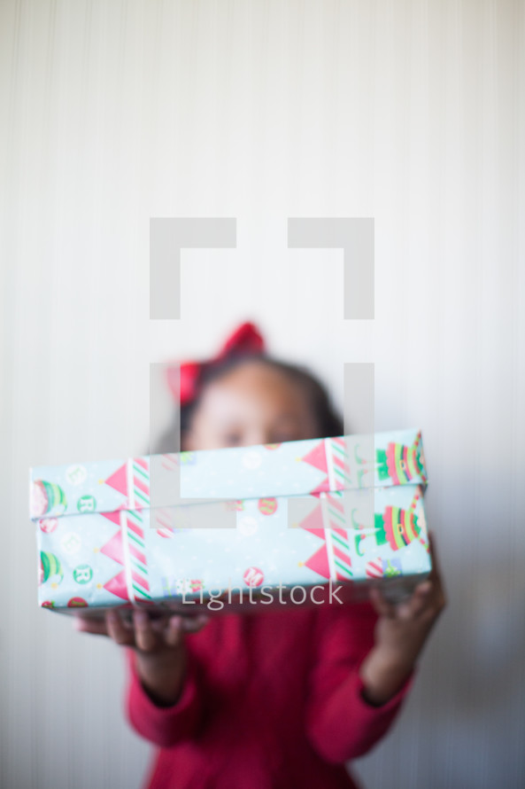 a girl child holding a wrapped Christmas present 