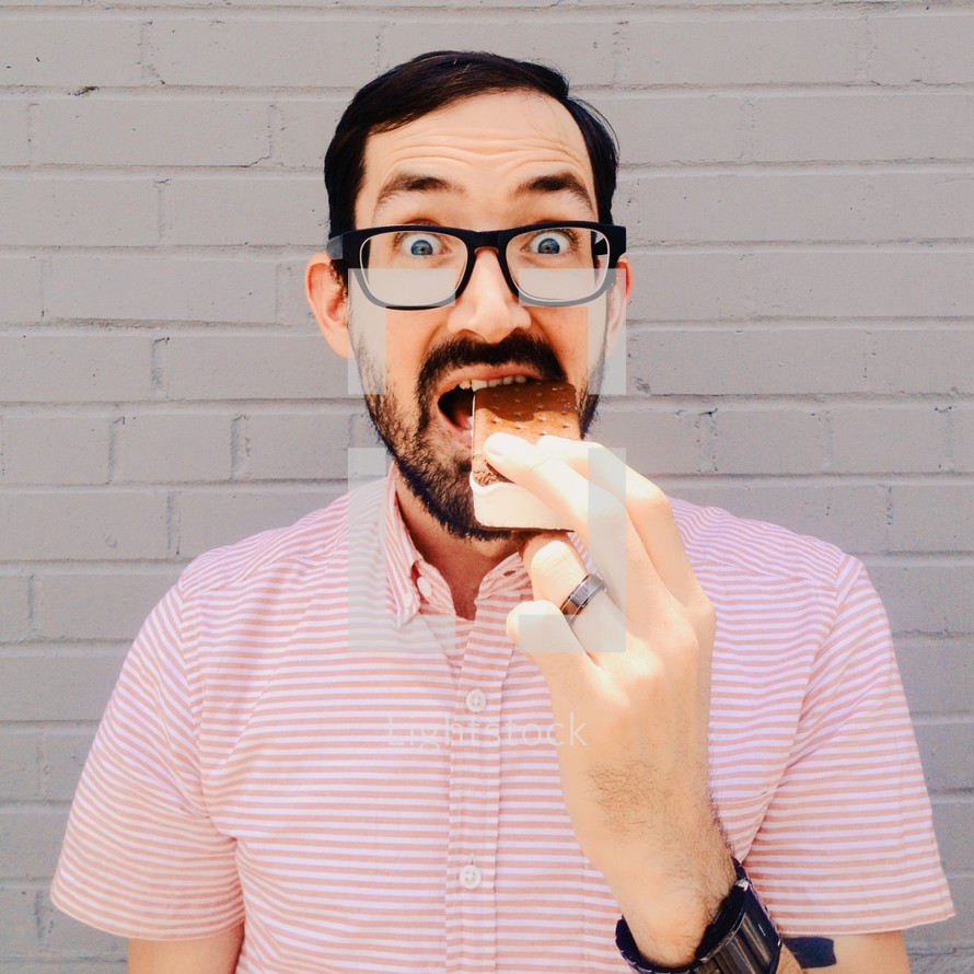 a man wearing glasses taking a bite out of a pizza 