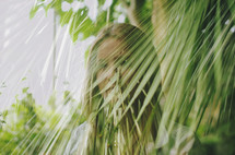 a woman standing behind palm fronds 
