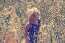 a toddler girl standing in tall grass 