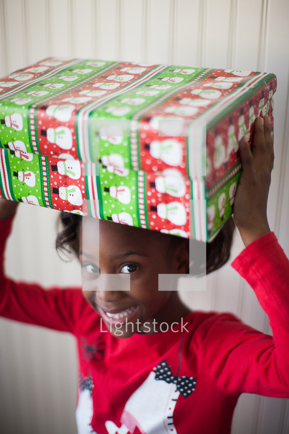 a girl child holding Christmas gifts over her head 