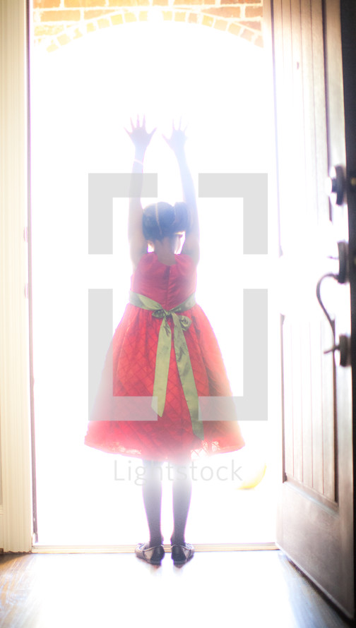 a girl child standing in sunlight from an open doorway 