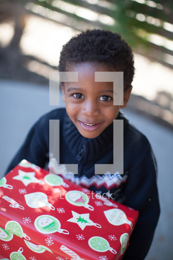 boy child holding a wrapped Christmas gift 