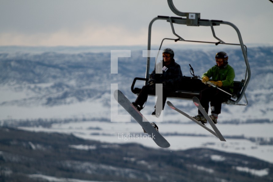 snow boarder and skier on a ski lift chair