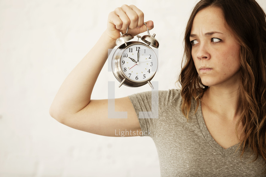 grumpy woman holding an alarm clock 
