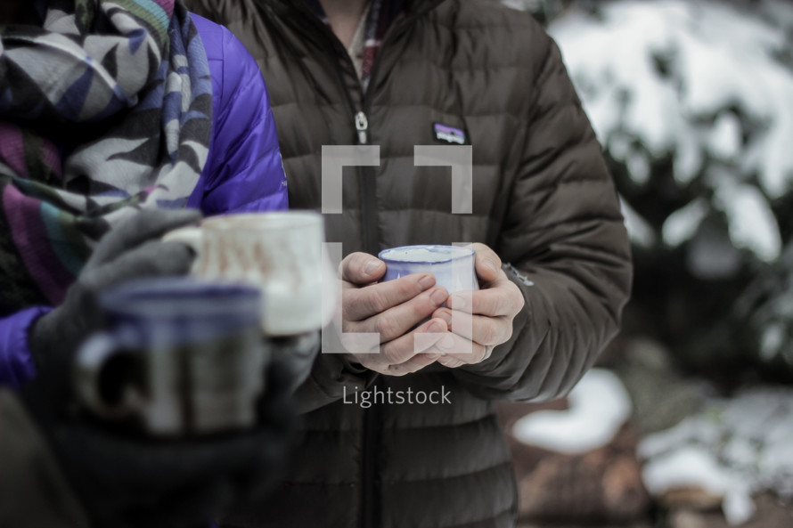 people with mugs standing outdoors in snow 