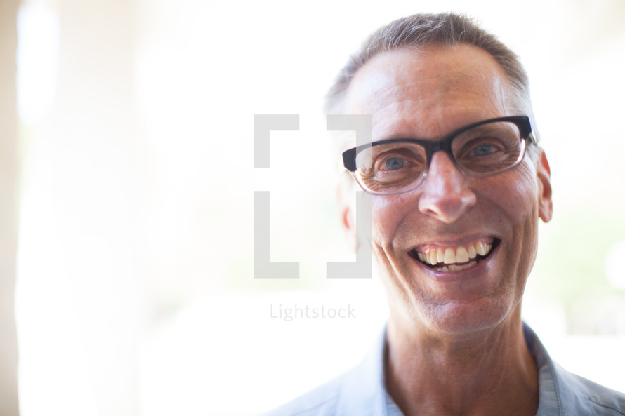 face of a smiling man wearing glasses 