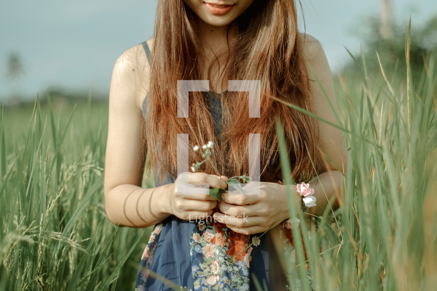 teen girl picking flowers in a field 
