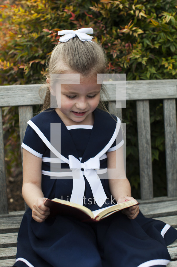 girl in a dress reading a book