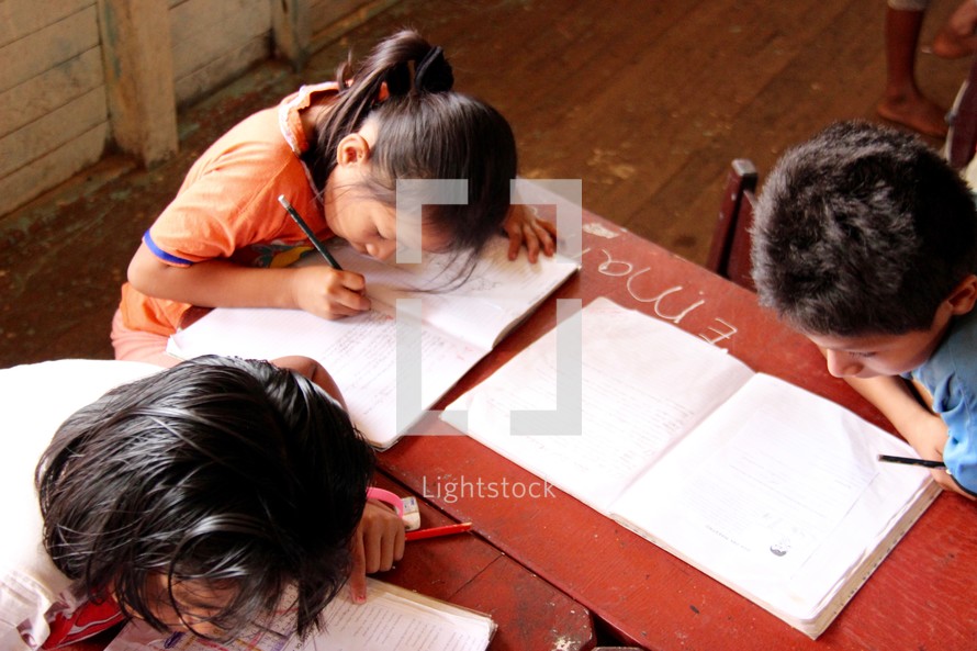 children studying at a table in a classroom 