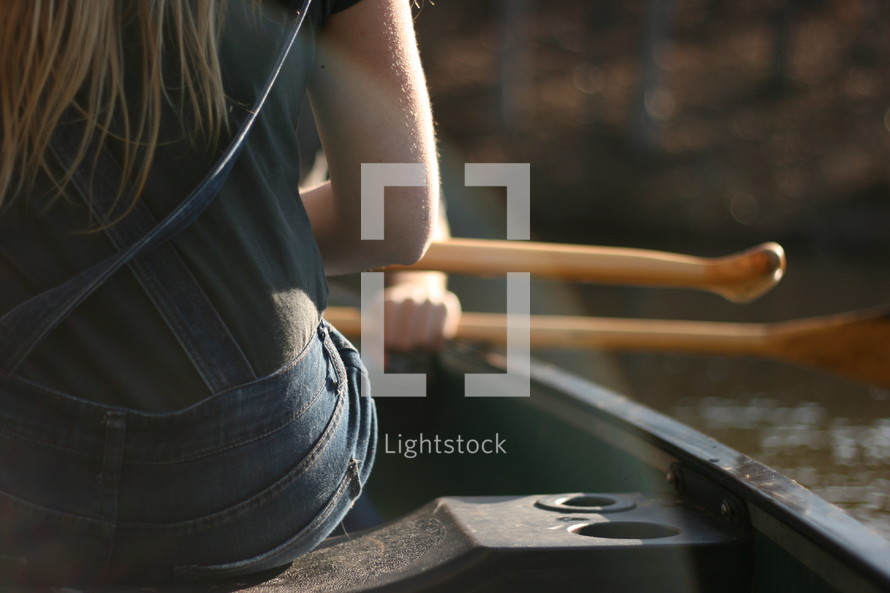 woman sitting on a boat holding paddles 