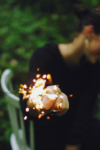 a woman holding a sparkler away from her face 