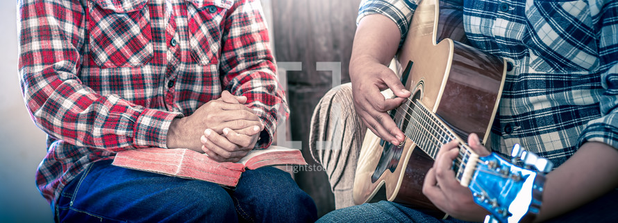 hands of young christians share a bible and sing with a guitar to worship God, Christian worship