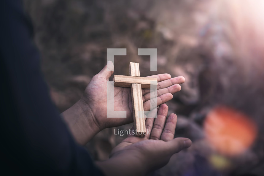 wooden cross in the palm of a hand outdoors 