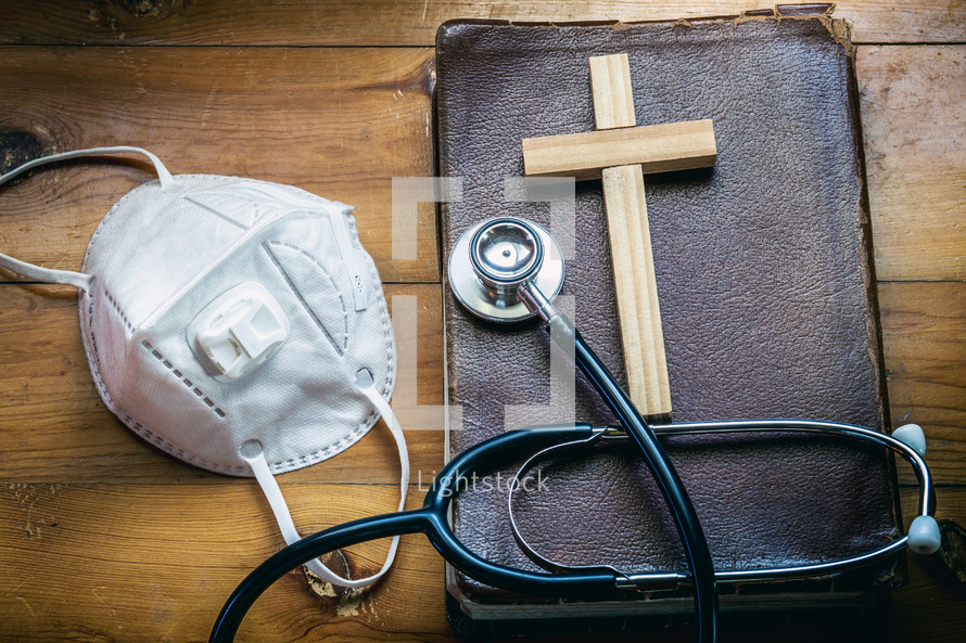 face mask, stethoscope, Bible, and wooden cross 