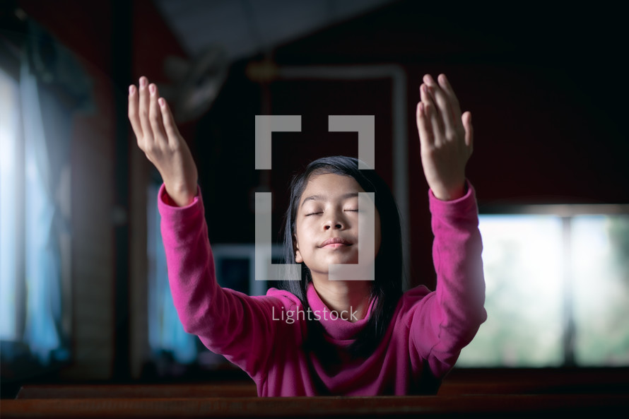 a girl with raised hands in a church 