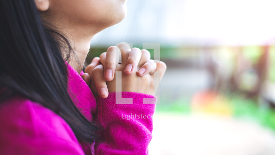 praying hands of a girl looking up to God 