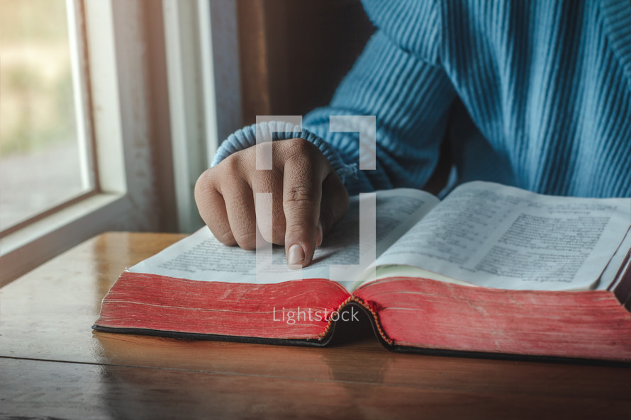 a person reading a Bible in a window 