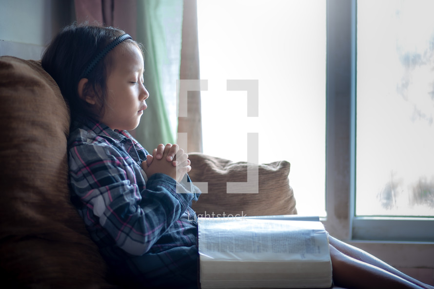a girl praying with a Bible in her lap 