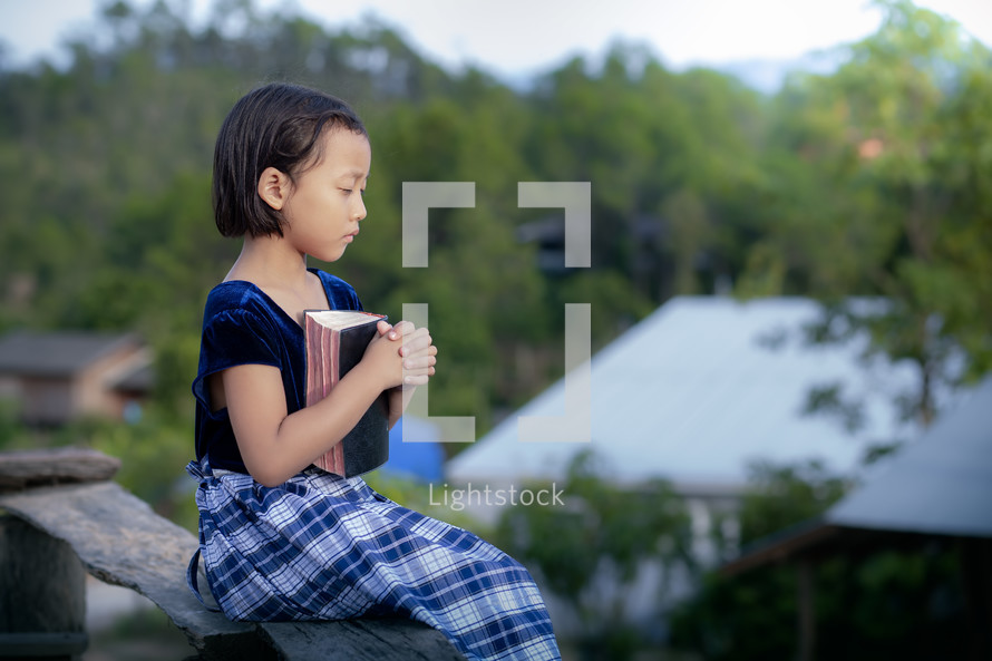 a girl holding a Bible praying 