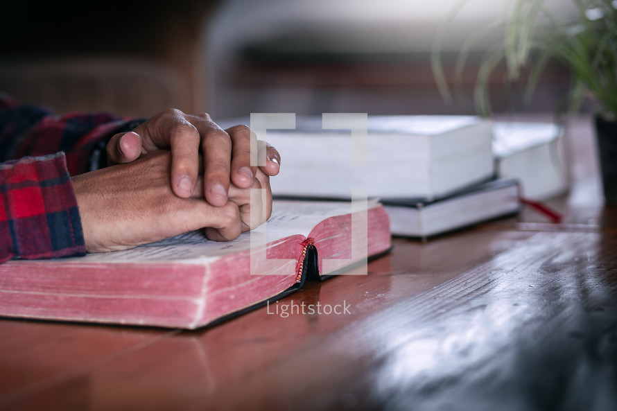 a man with hands over an open Bible 