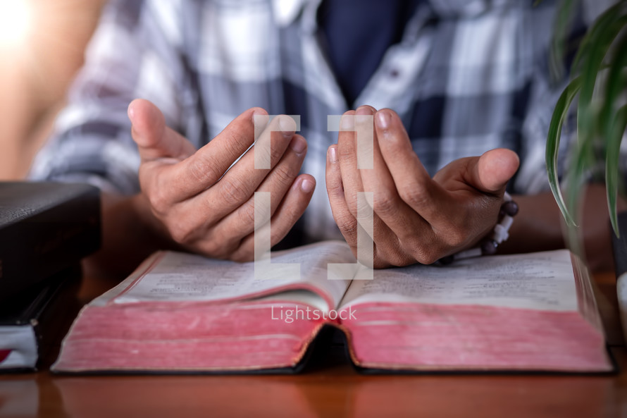 lifted hands over an open Bible 