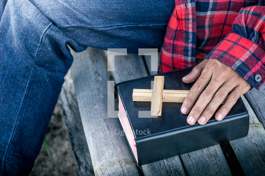 a man sitting next to a Bible and wooden cross 
