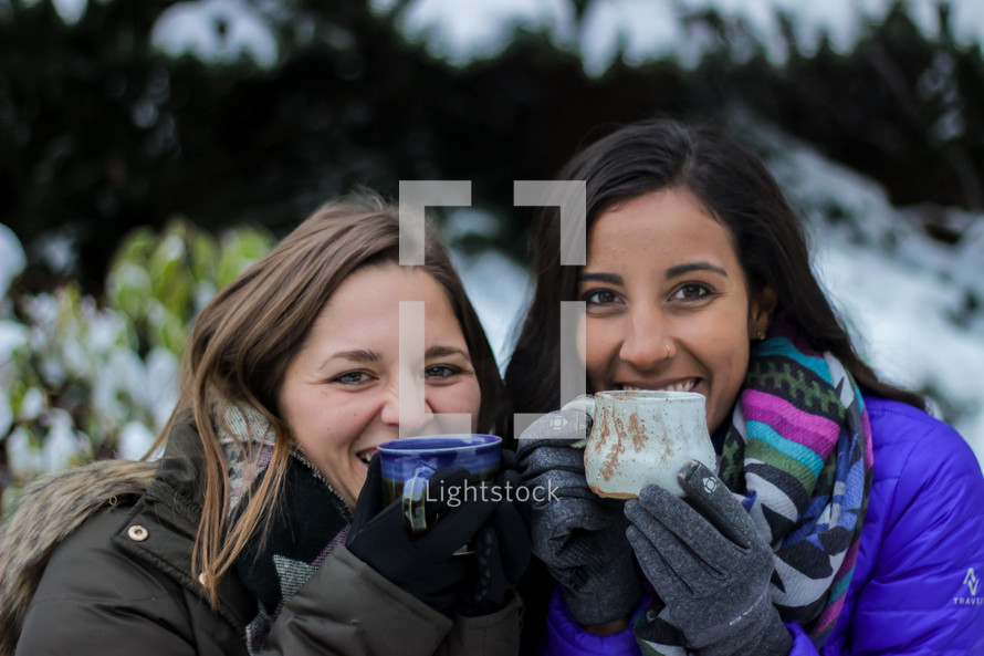 women with mugs standing outdoors in winter 