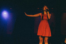 A young woman singing on stage.