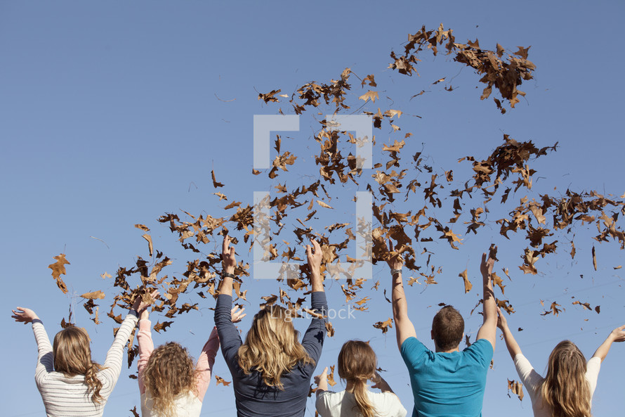 Group of friends throwing leaves in the air.