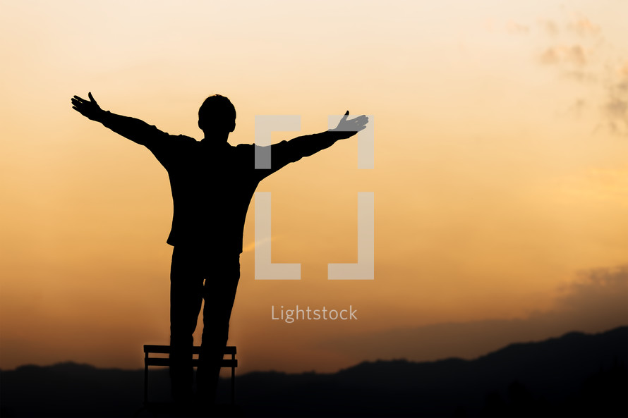 a silhoutte of a boy with raised hands 