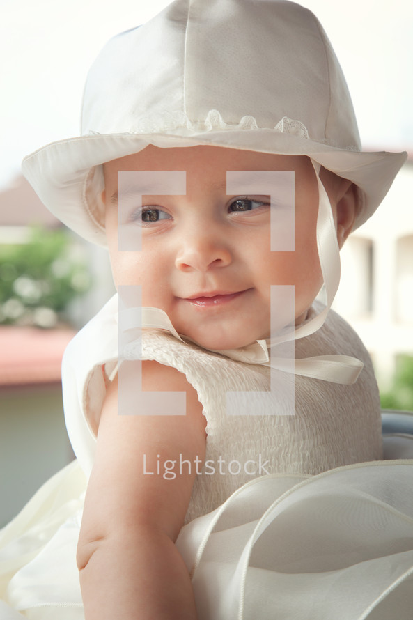 child a few months with white dress and hat on the day of her baptism
