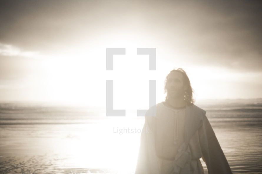 Jesus standing on a shore surrounded by glowing light 