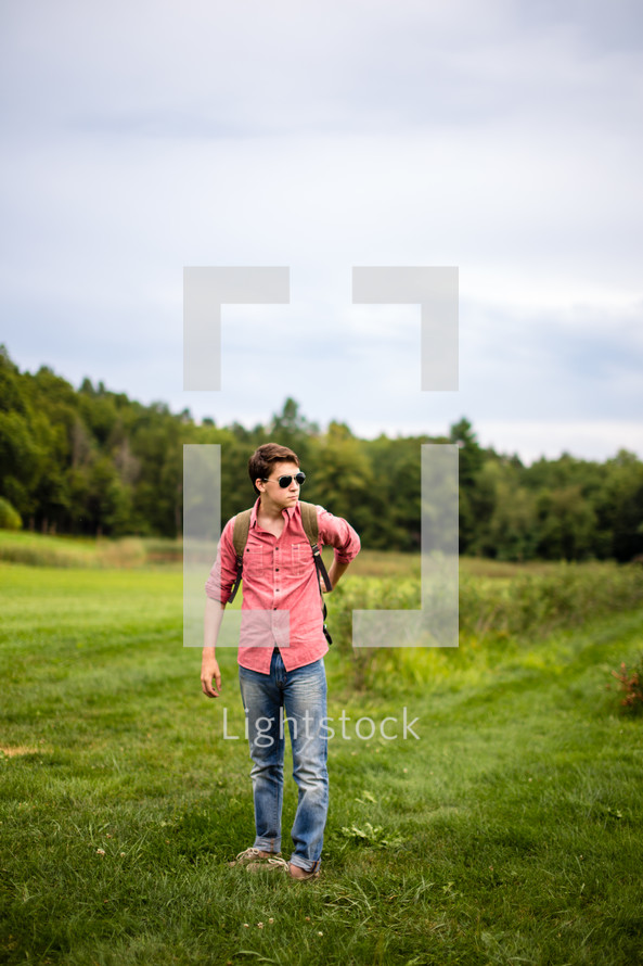 man in a field with a backpack 