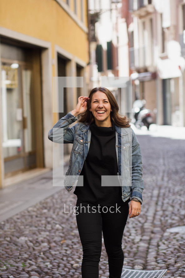 a woman standing in the middle of a cobblestone street 
