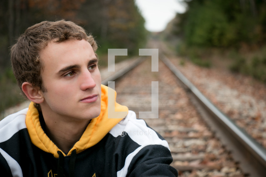 man sitting on railroad tracks 
