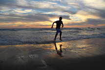 teen boy running in the ocean