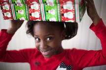 a girl child holding a Christmas gift over her head 