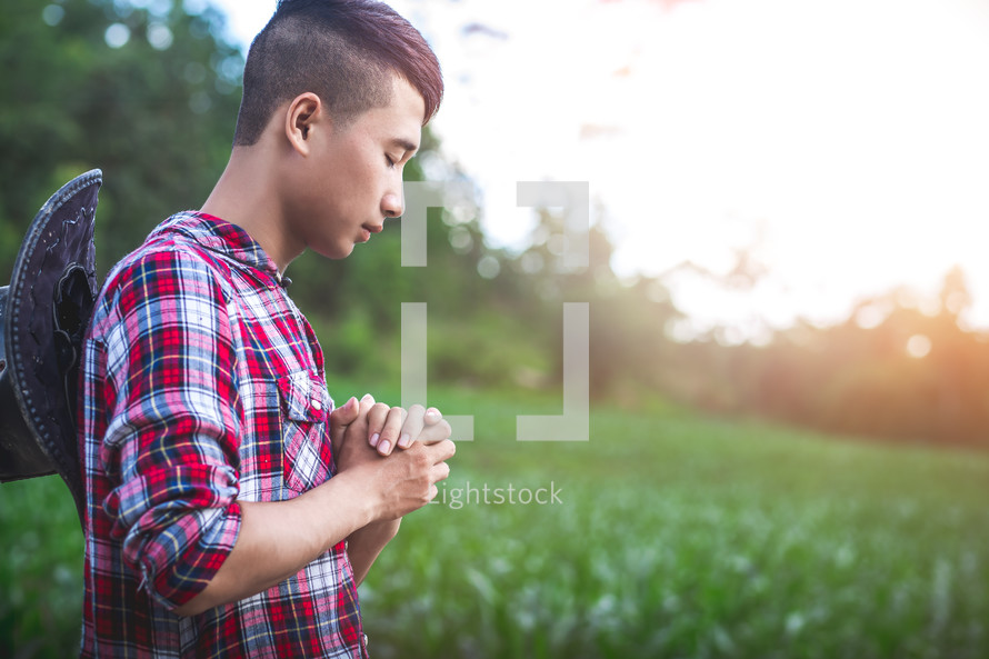 Young farmer praying in corn field